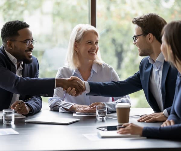 Smiling business people shake hands and get acquainted greeting at a team meeting in the office