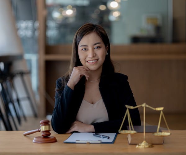 Smiling woman lawyer sitting in office with a gavel & scale and with some documents