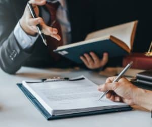 Client signing an agreement in front of a lawyer