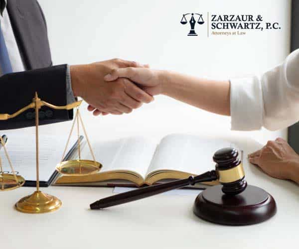 Lawyer consultant with client shaking hands together with a gavel, scale & books